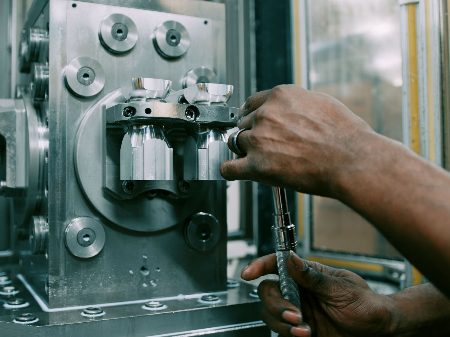 Close-up of hands using wrench to work on industrial metal machinery equipment.