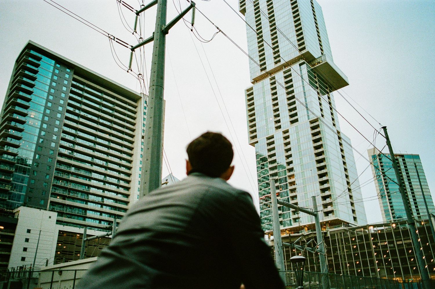 Man in suit gazing up at modern high-rise skyscrapers in an urban city landscape.