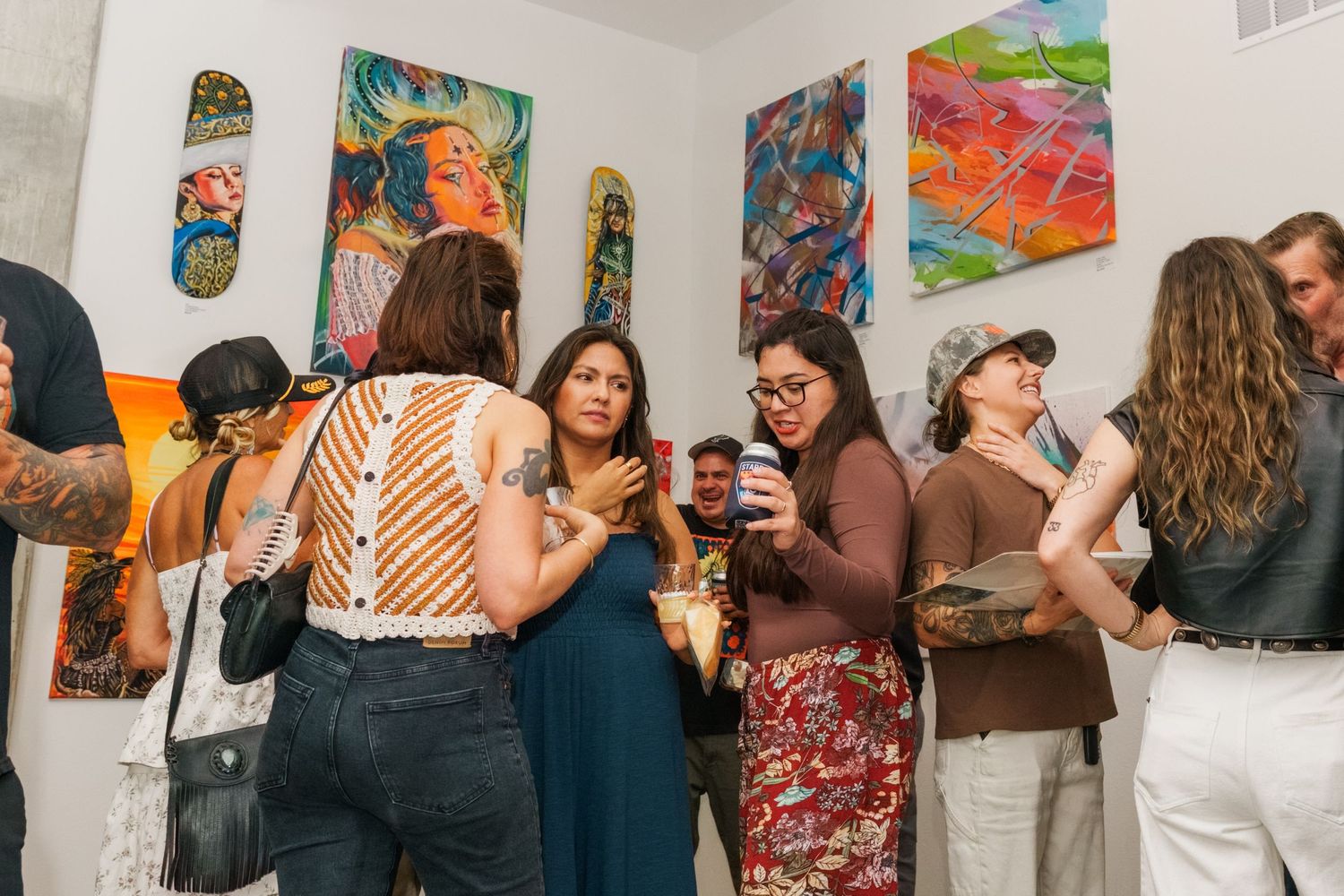 Diverse group of people socializing at a vibrant art gallery opening event.