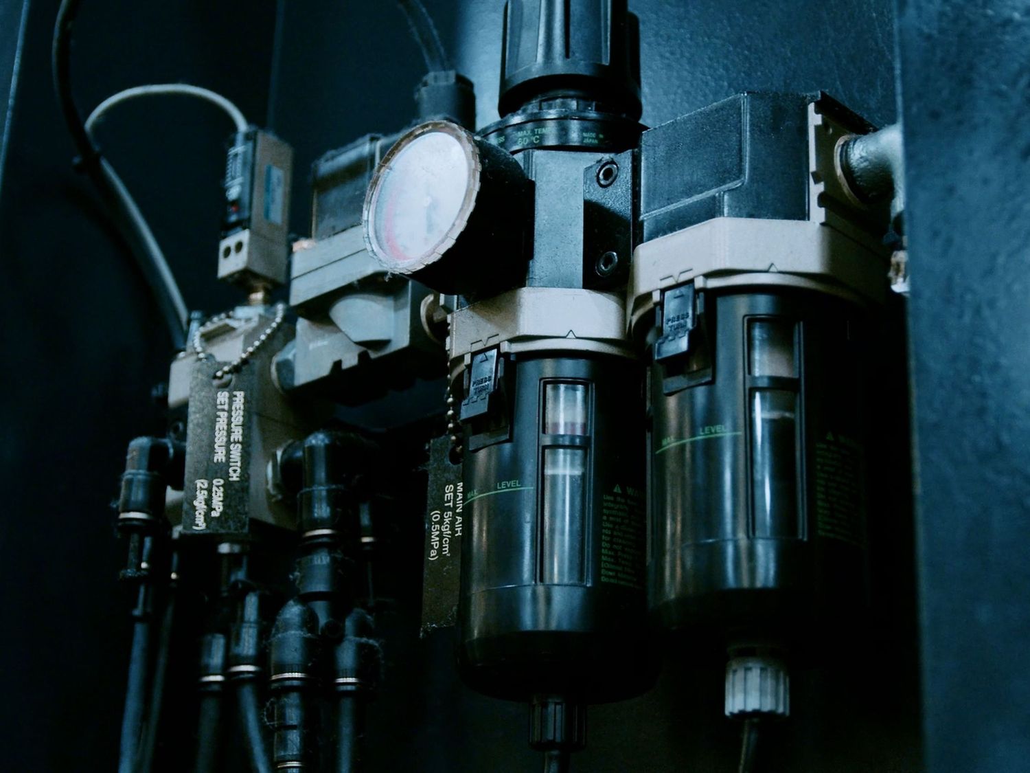Industrial pneumatic filter regulator assembly with gauges mounted on dark machinery panel.