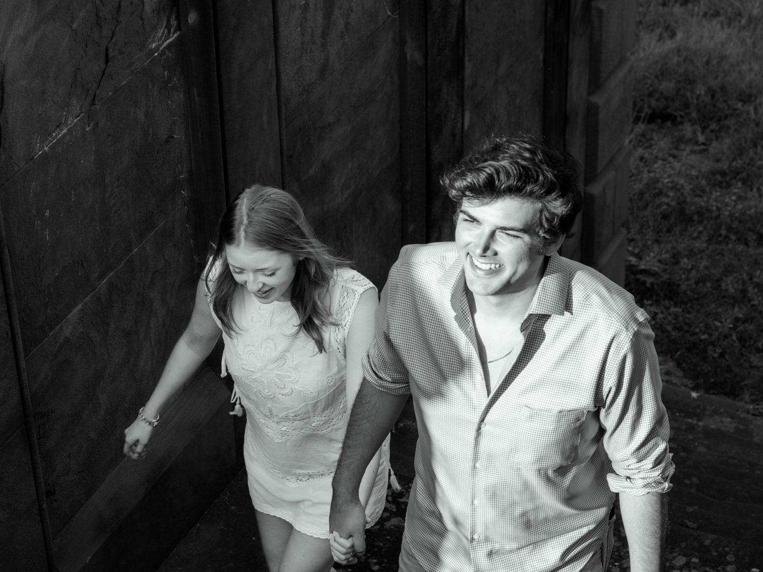 Black and white photo of a couple holding hands walking down outdoor steps together.