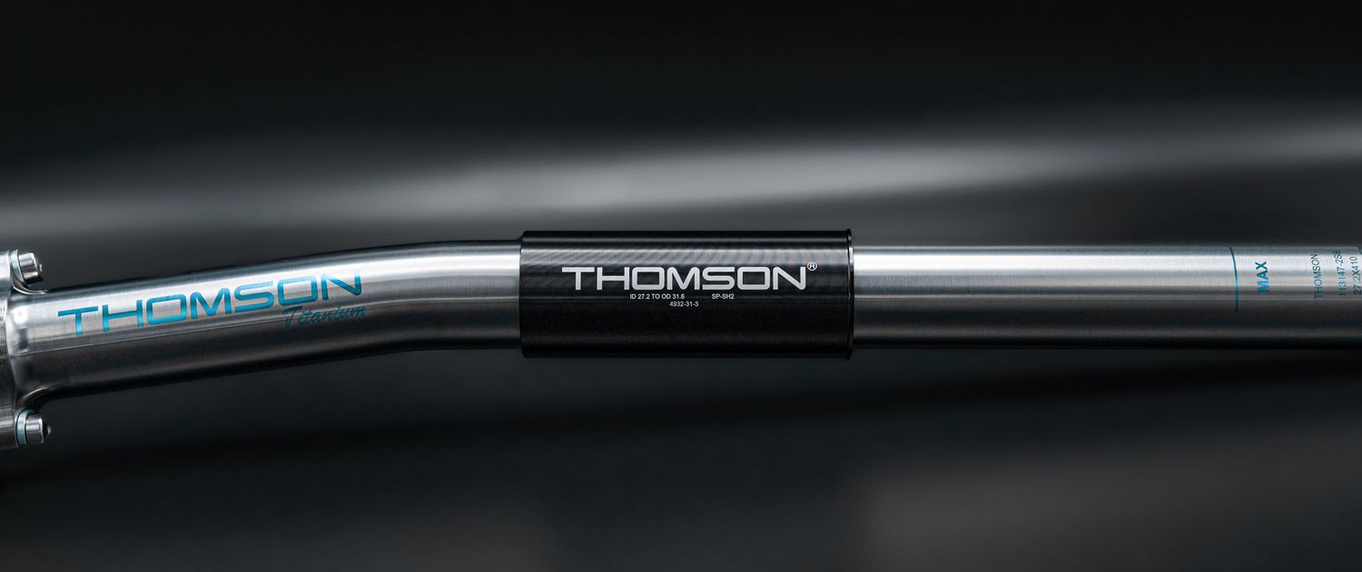 Thomson branded bicycle handlebar with black clamp collar on a sleek silver mountain bike handlebar.