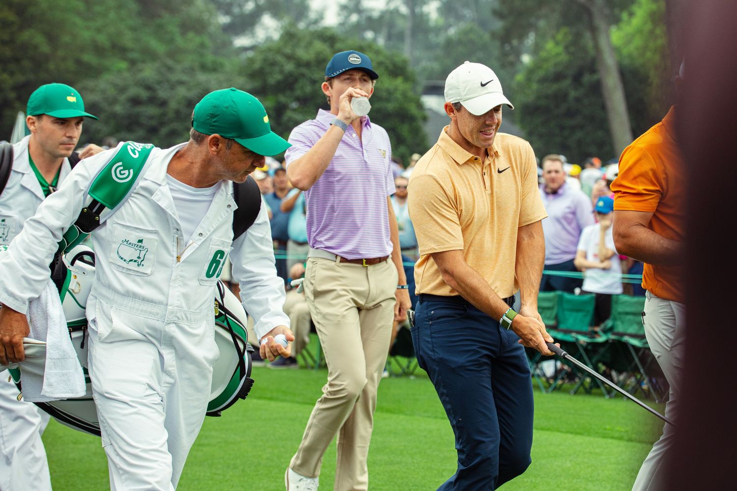 Golfers and caddies walk the fairway at Augusta National Golf Club during the Masters Tournament.