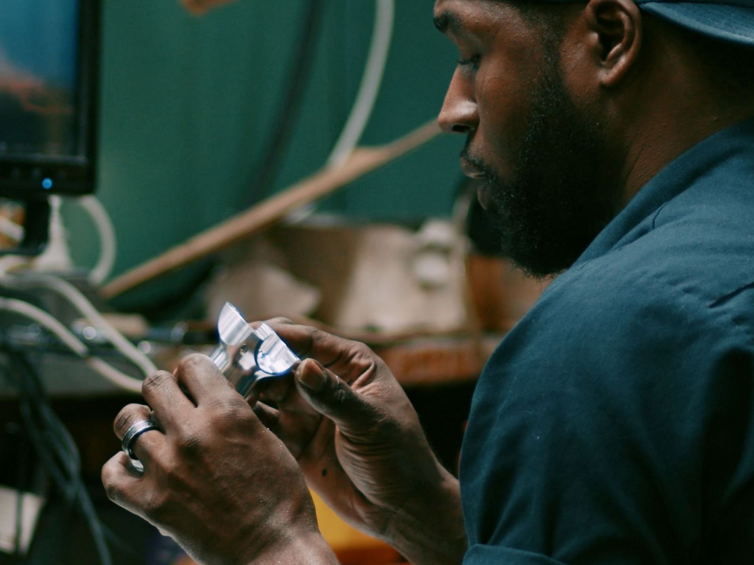 Skilled craftsman carefully examines a small machined metal part under close inspection.