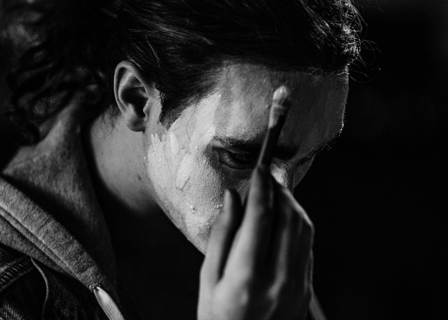 Black and white close-up of emotional person with hand covering face.