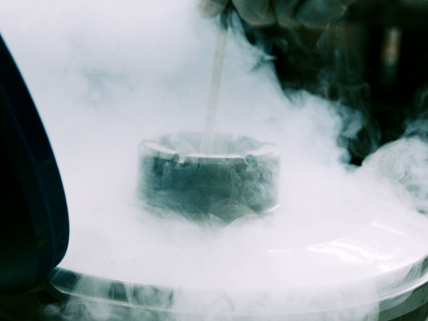 Liquid nitrogen creates dramatic white smoke around a metal industrial component.