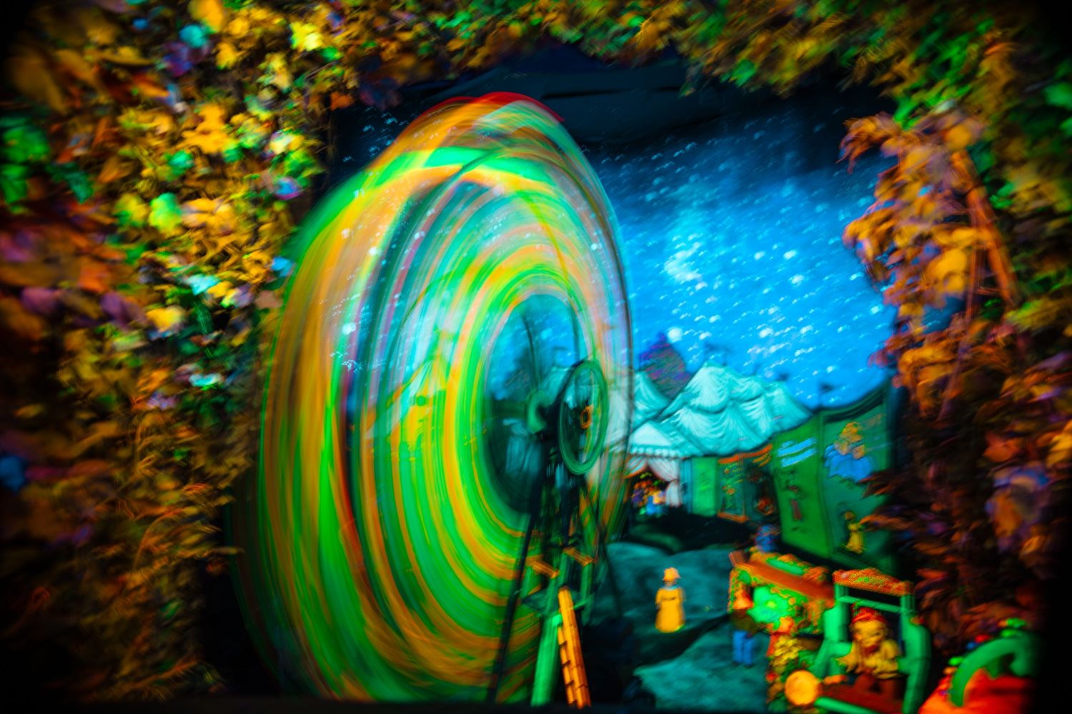 Colorful spinning vortex tunnel with vibrant green and yellow swirls in a neon-lit immersive art installation.