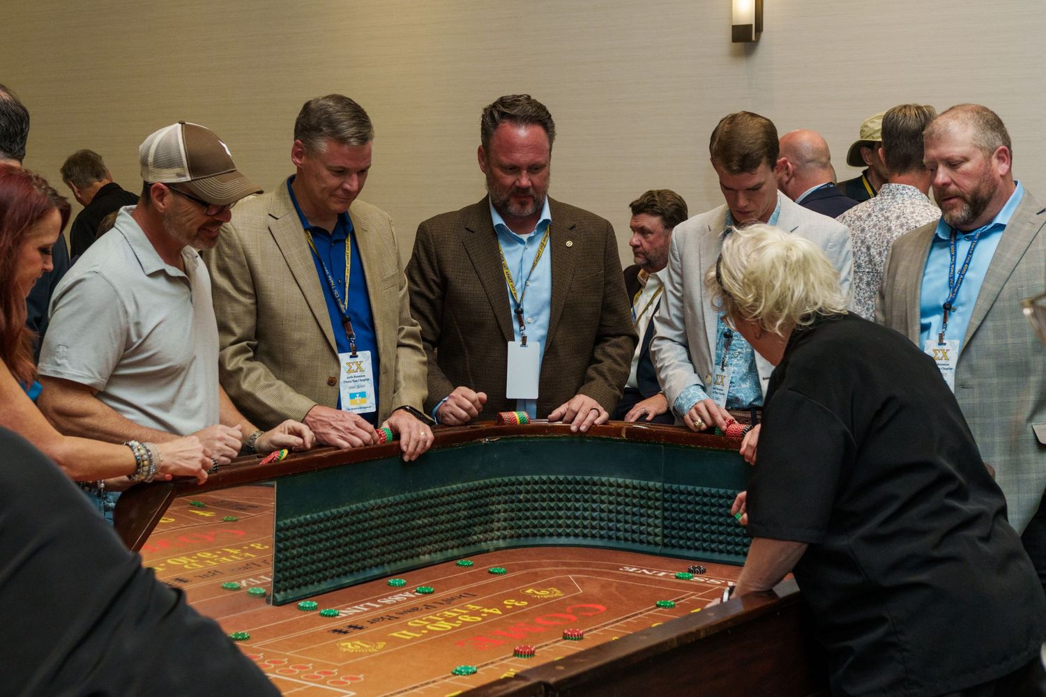 Group of professionals gathered around a casino roulette table at a corporate event or charity fundraiser.