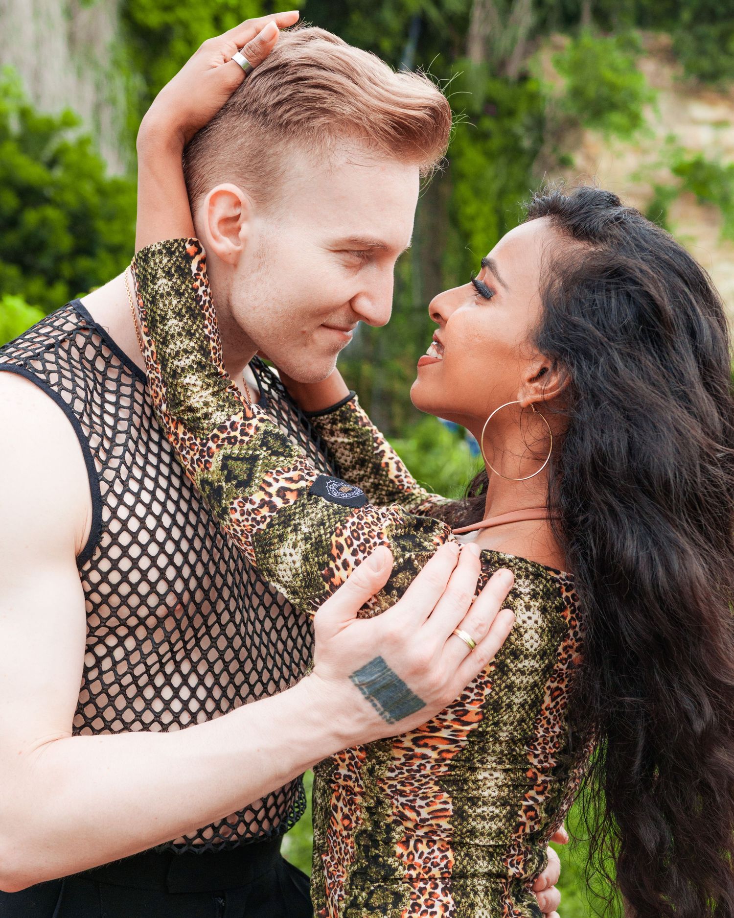 Close couple in bold animal print outfits facing each other intimately outdoors.