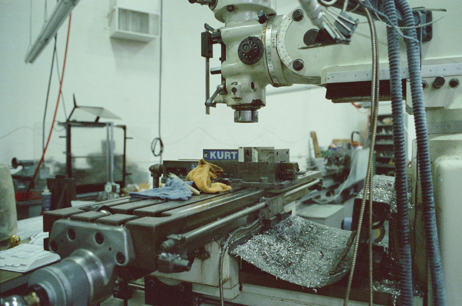 Industrial milling machine with Kurt vise in a metal workshop with shavings.