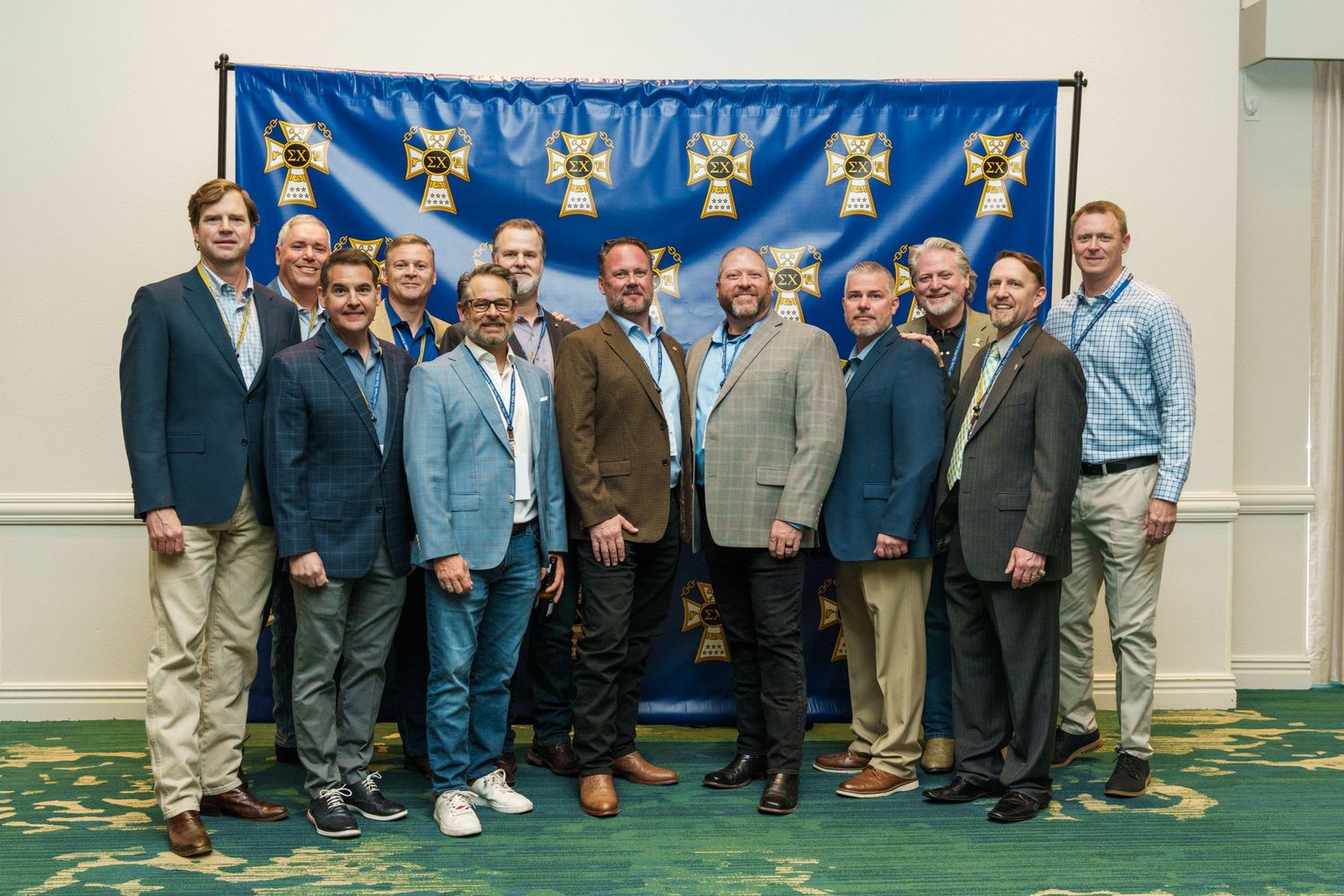 Group of professionals posing together in front of a blue banner at a formal business or organizational event.