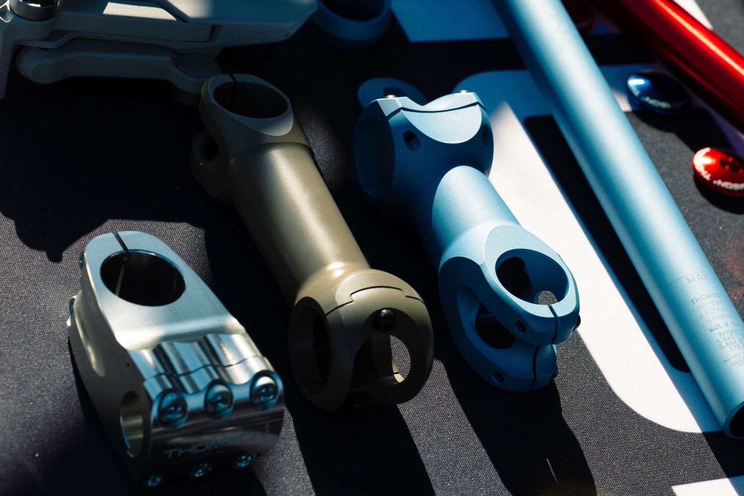 Collection of mountain bike stems in various colors including blue, tan, and silver on display.