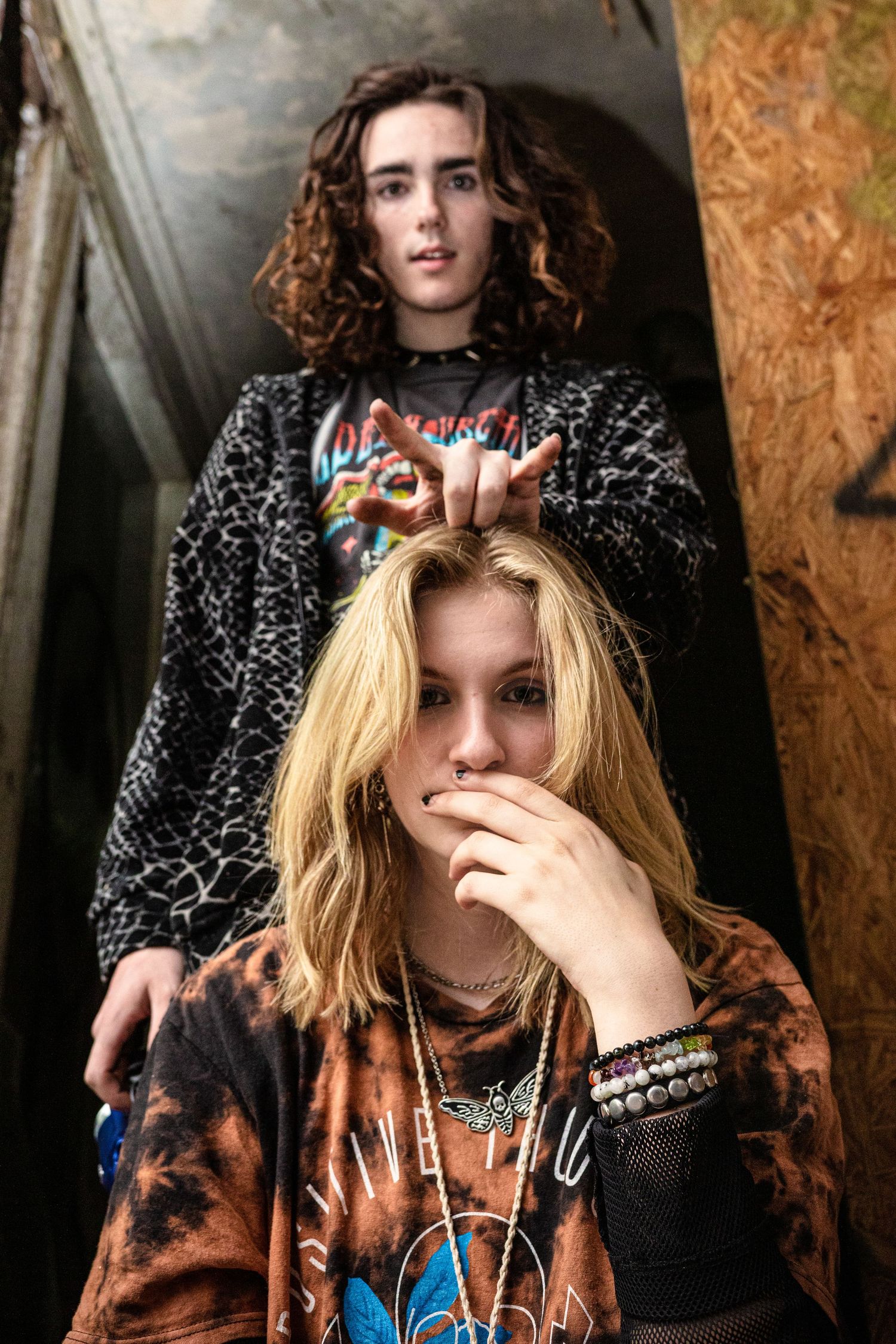 Two edgy young teens pose in an urban stairwell wearing vintage rock graphic tees.