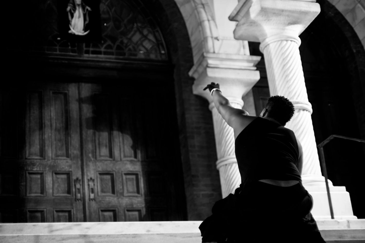 Black and white photo of a person photographing ornate church doors and columns at night.
