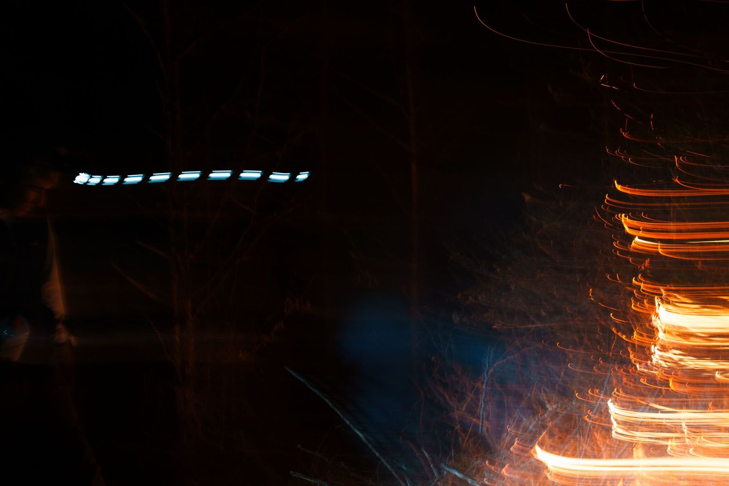 Abstract long exposure night photography showing streaks of orange and blue light against a dark background.