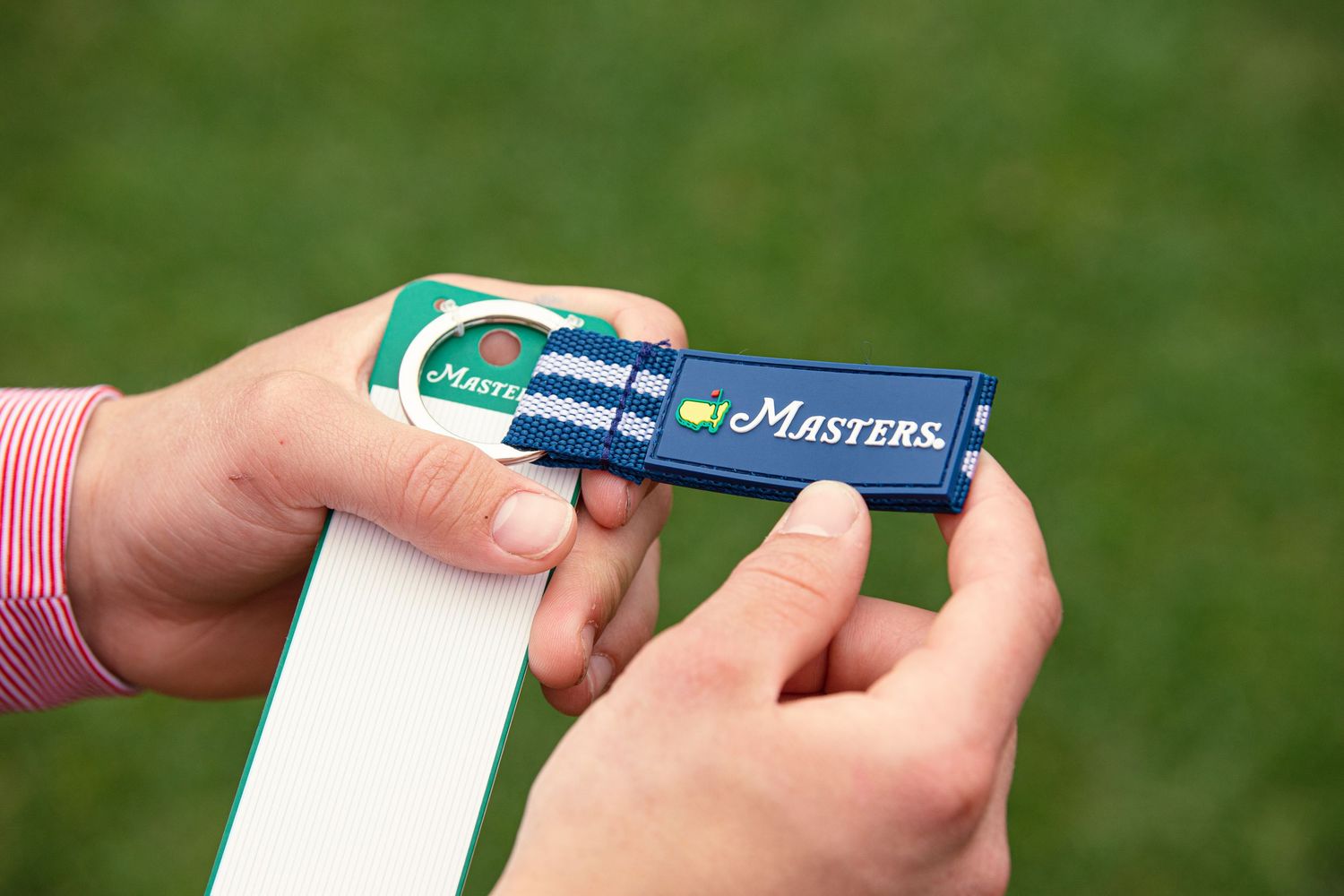 Hands holding an eMasters branded USB flash drive at the Masters golf tournament.