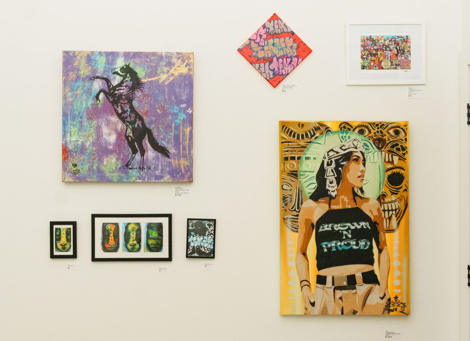 Colorful mixed media artwork displayed on white gallery wall including pop art and street art.