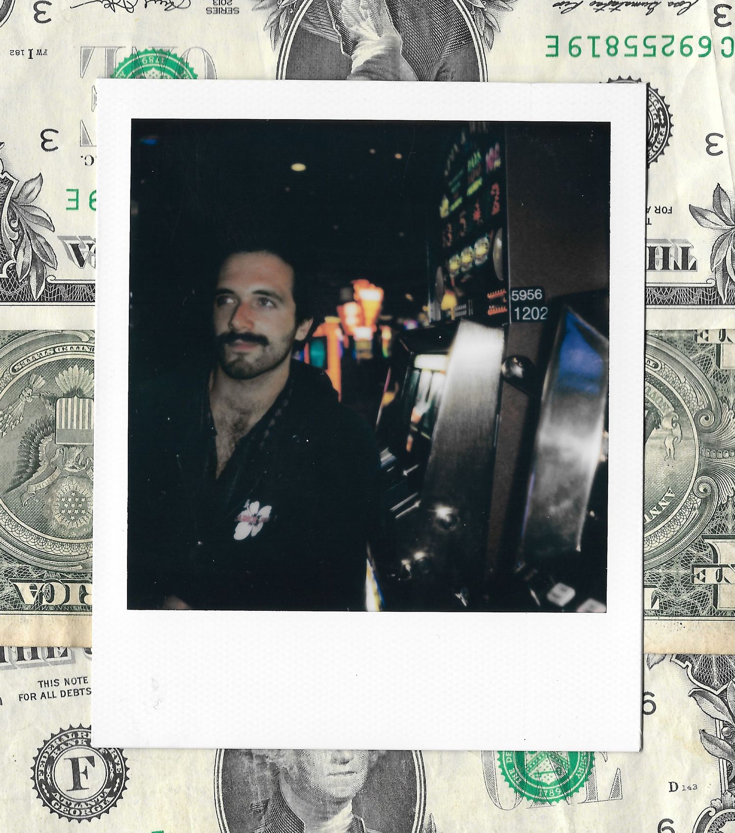 Polaroid photo of a bearded man standing next to a slot machine in a casino, framed by dollar bills.