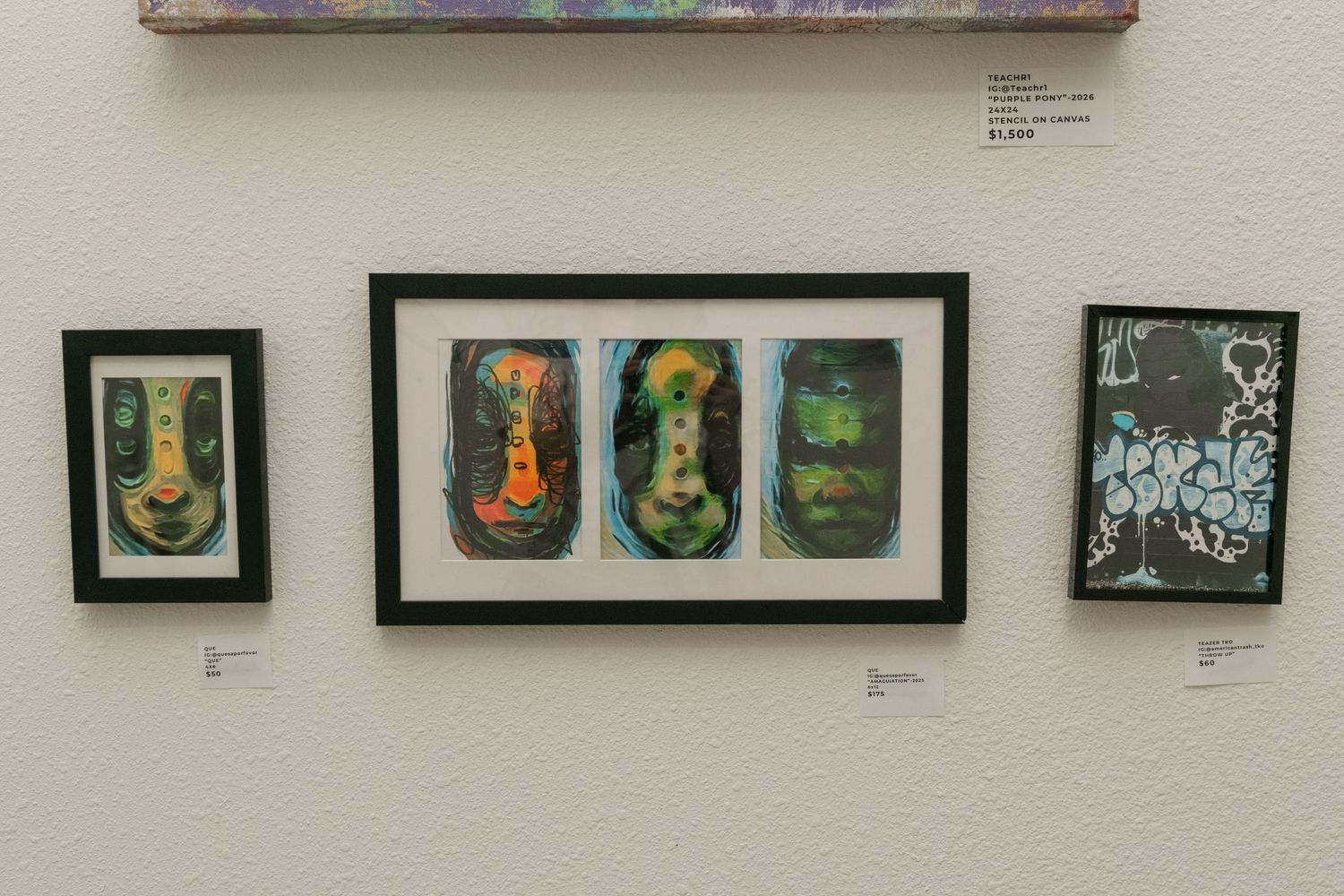 Three framed abstract face artworks displayed on a white gallery wall with price tags.