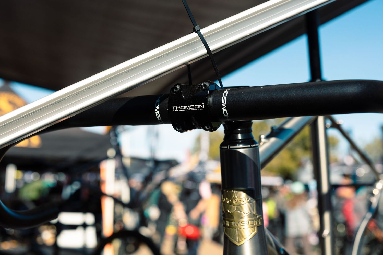 Thomson branded black handlebar stem and seatpost on a bicycle at an outdoor cycling event.