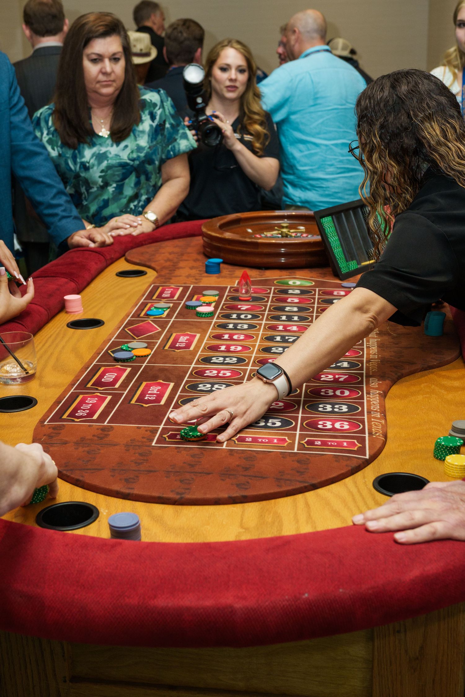 People playing roulette at a casino table, with chips and a roulette wheel visible in a lively gaming environment.