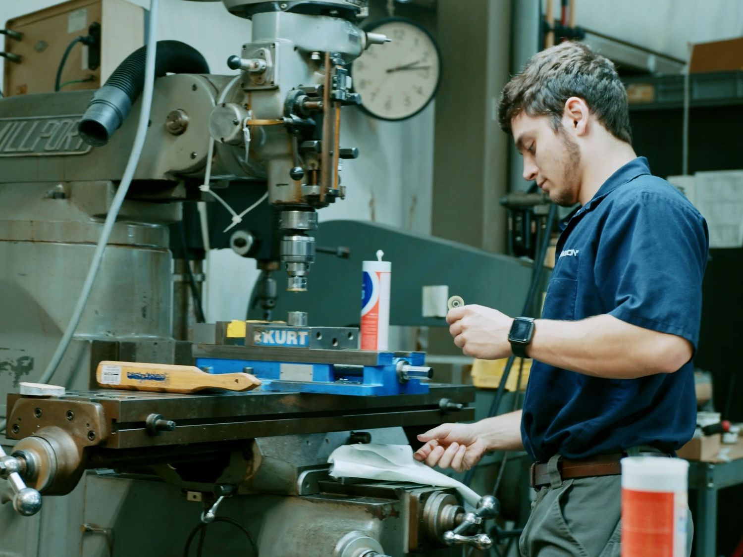 Young technician operates precision milling machine in professional manufacturing workshop.