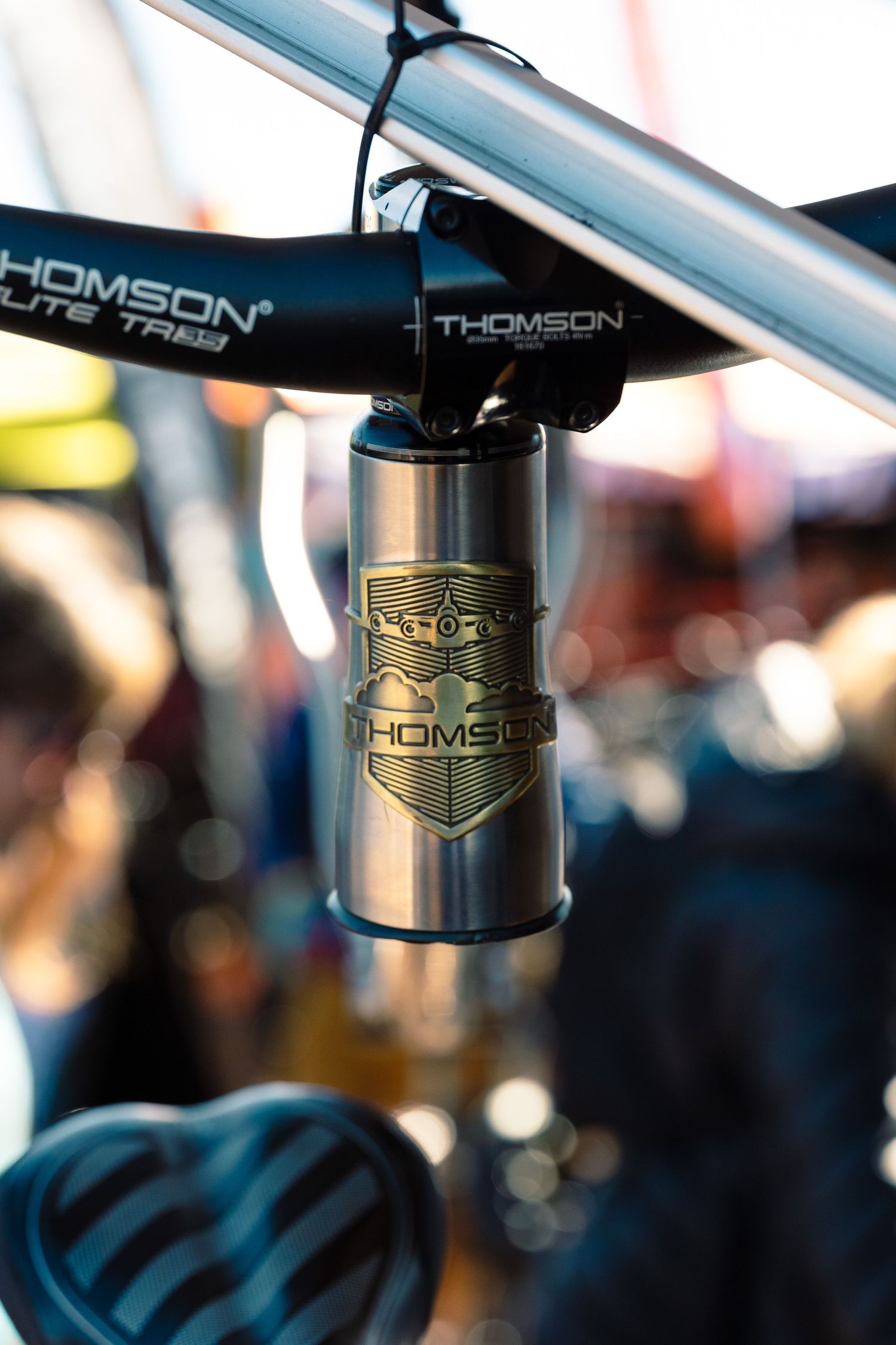 Close-up of a Thomson Elite stem and seatpost on a bicycle at an outdoor cycling event.