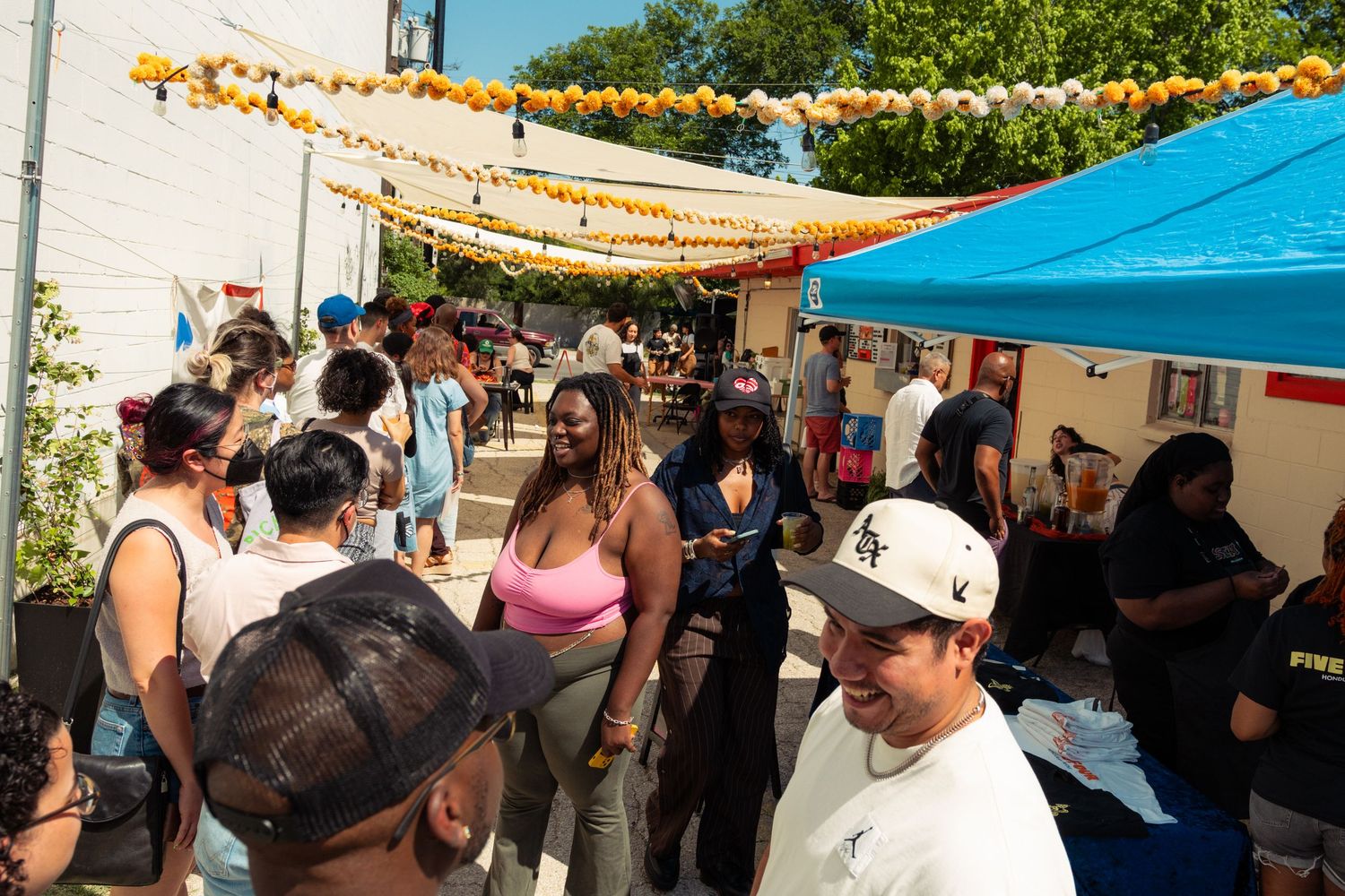 Crowded outdoor art market with colorful decorations and vendor booths on a sunny day.