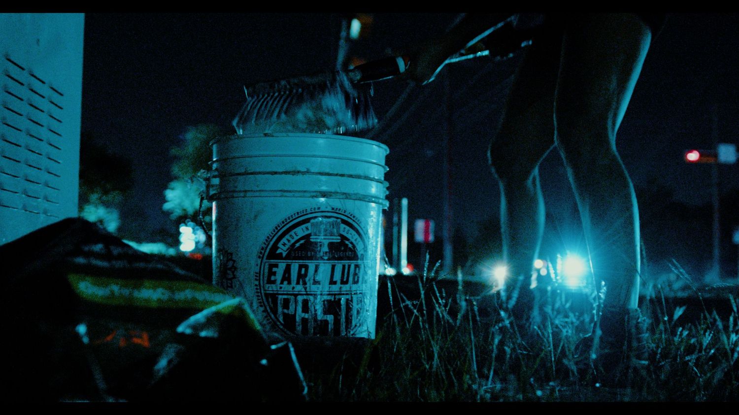 Mysterious night scene with glowing bucket labeled 'Explosive' amid dark grass and eerie creature silhouette.