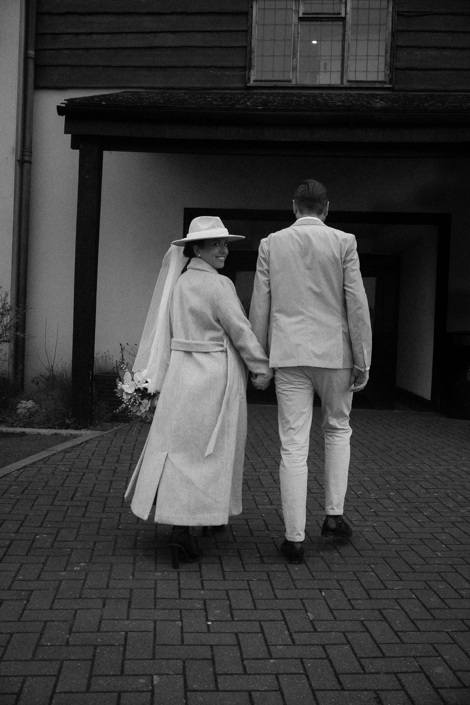 Black and white wedding photo of newlywed couple walking hand in hand