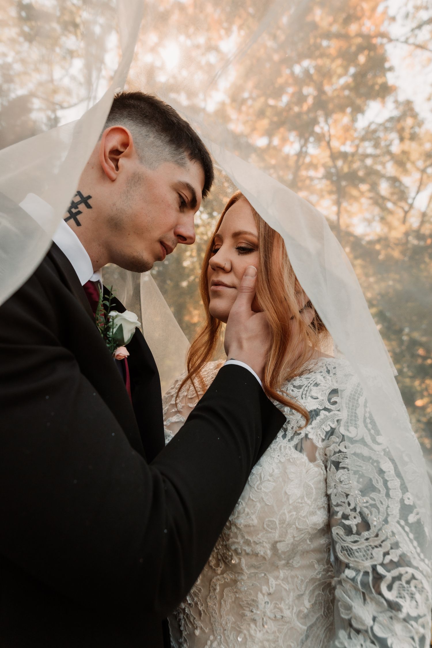 A romantic wedding moment captured in soft autumn light with a couple in traditional attire sharing an intimate embrace.