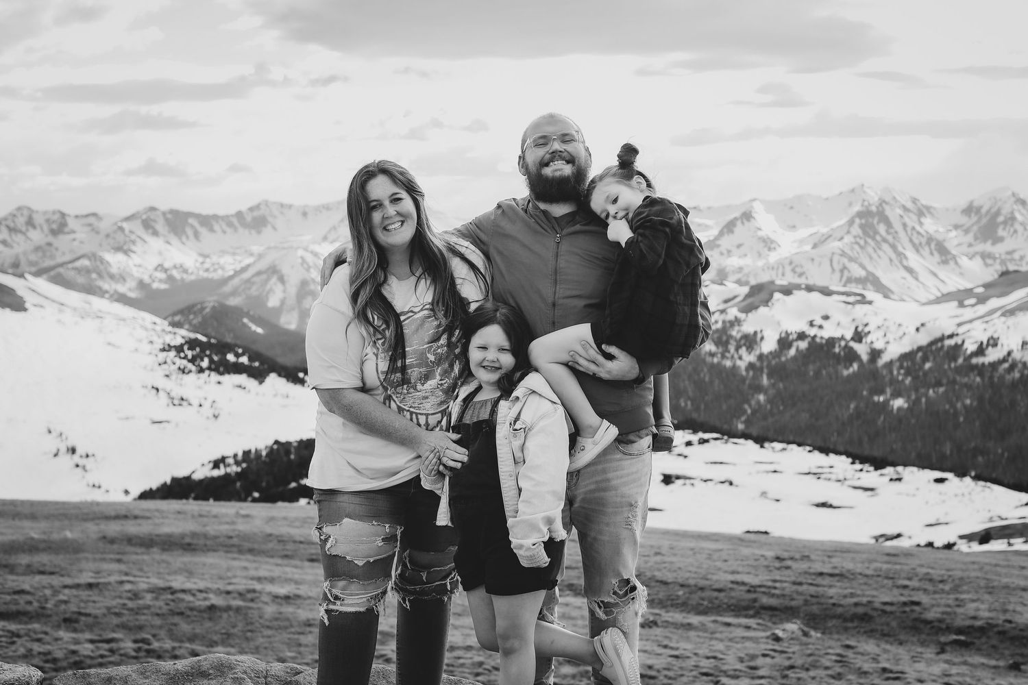 Black and white portrait of a family standing together on a mountain overlook.