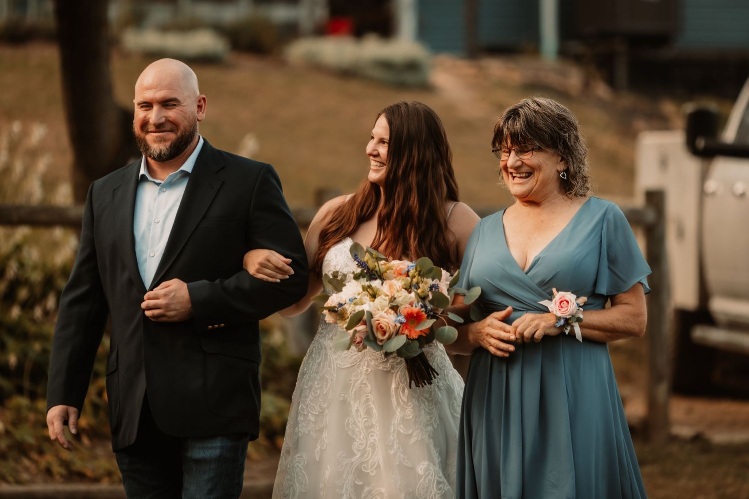 A wedding party walks arm in arm while the bride holds a beautiful peach and cream floral bouquet.