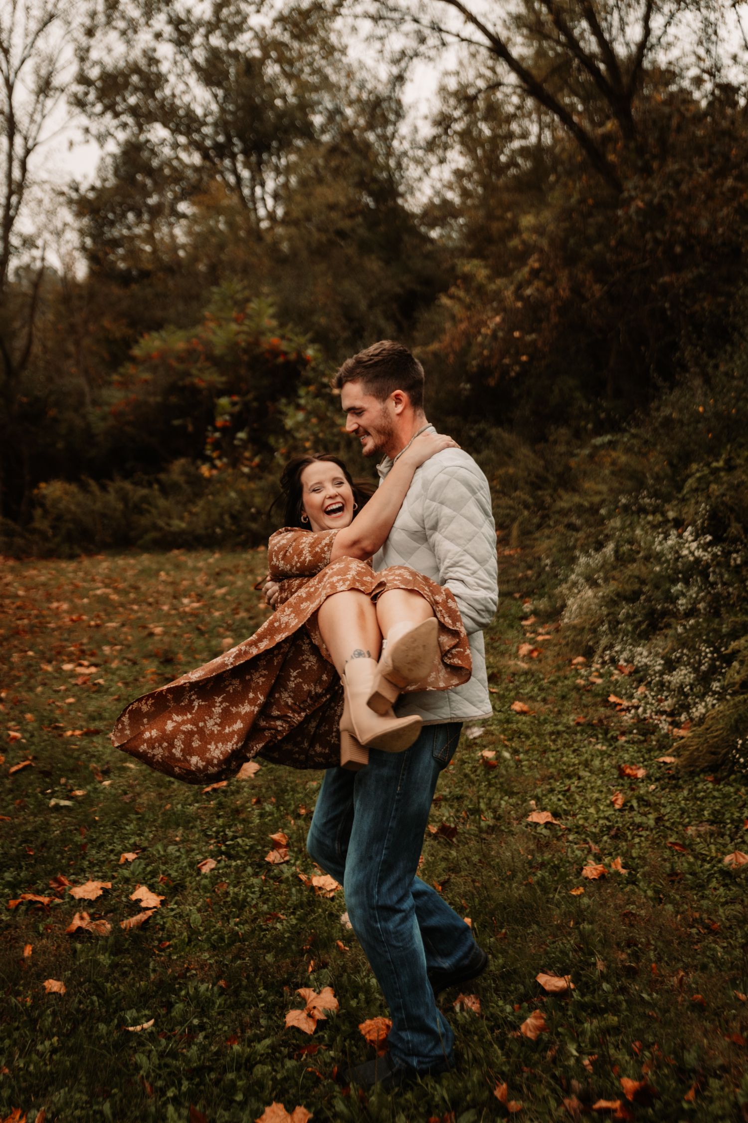 Parent and child share a joyful moment playing together in an autumn garden with fallen leaves.