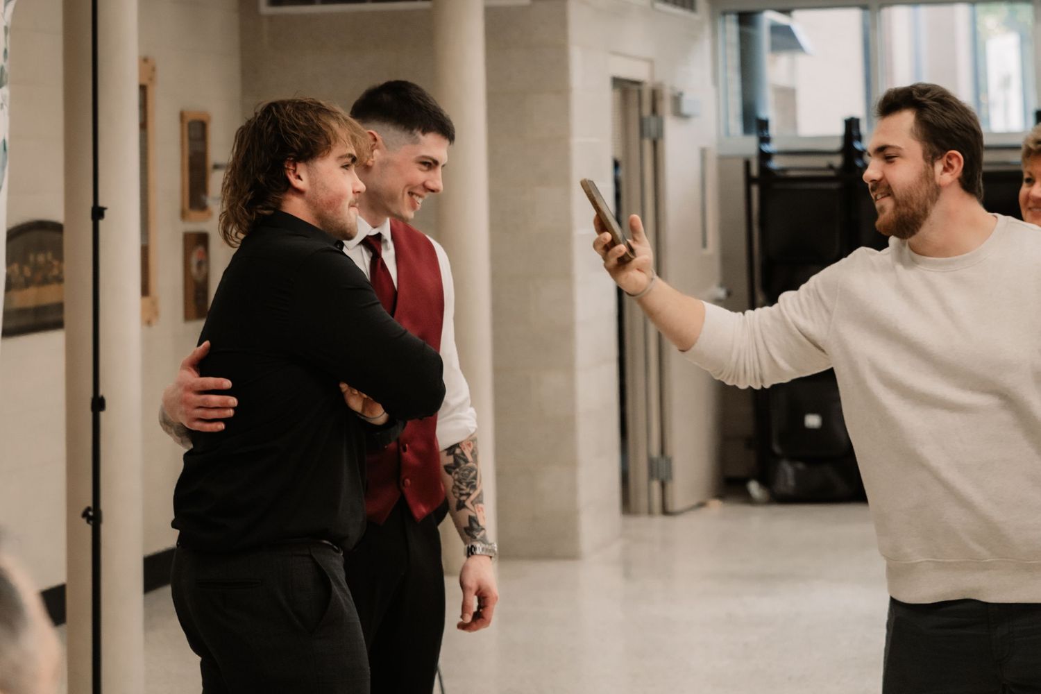Three people sharing a lighthearted moment and laughing together in an indoor hallway.