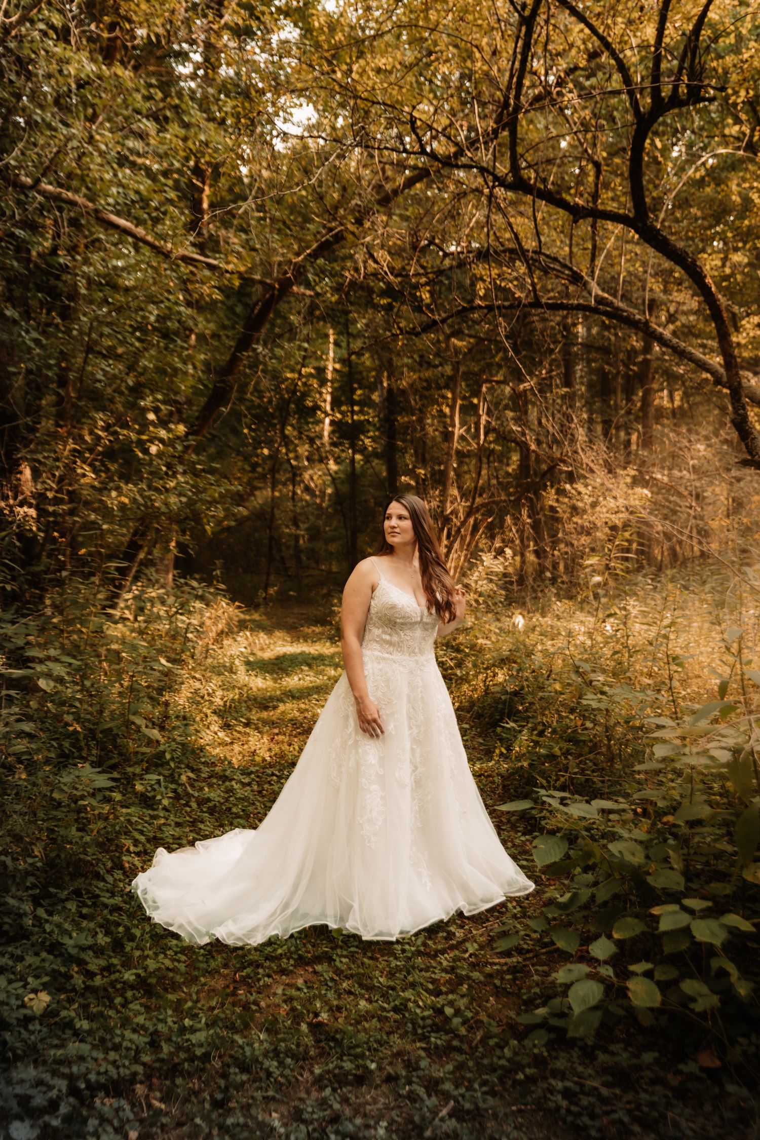 A bridal portrait in a dreamy forest setting with golden sunlight filtering through autumn trees.
