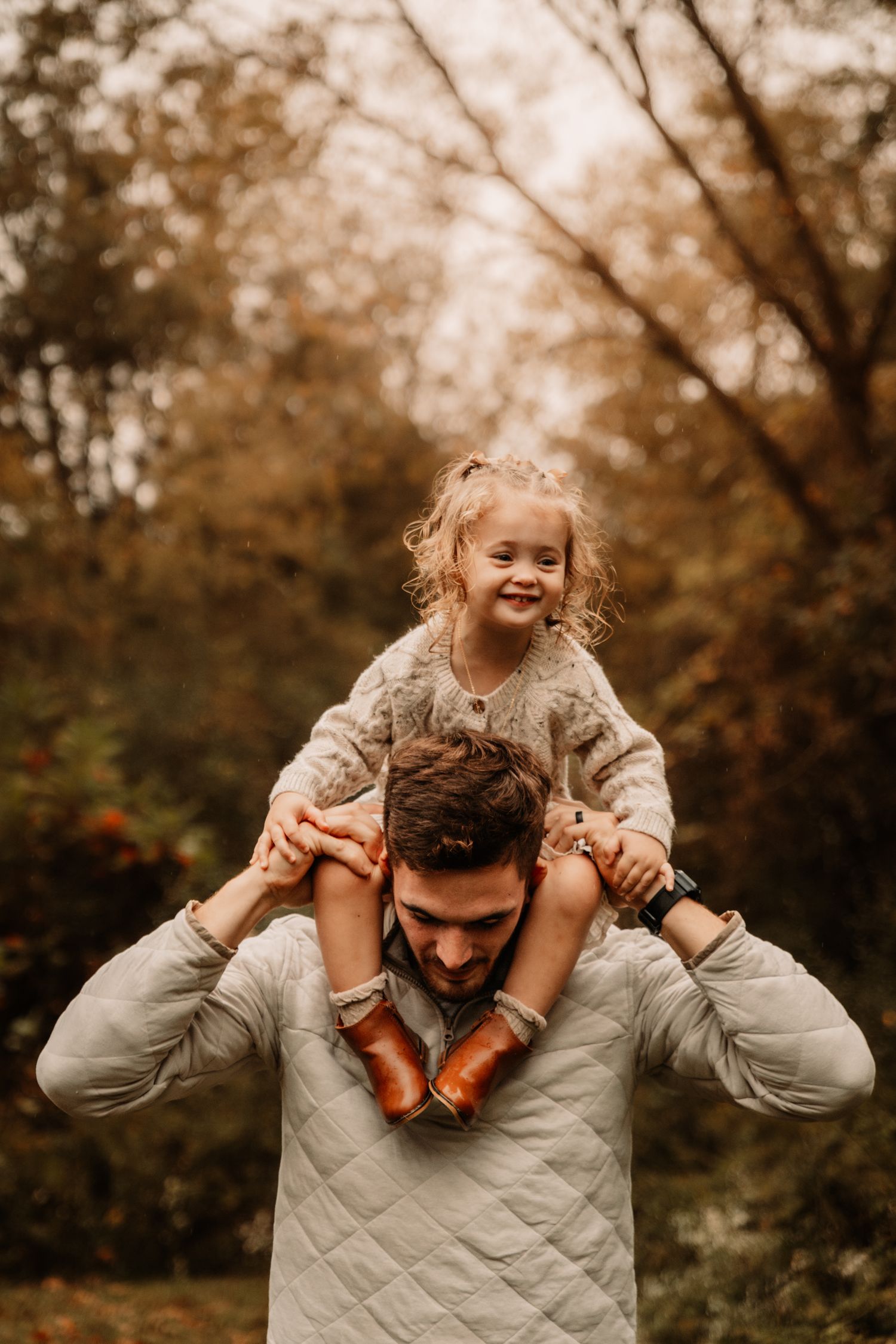 A heartwarming autumn scene shows a child riding on shoulders surrounded by fall foliage in warm sepia tones.