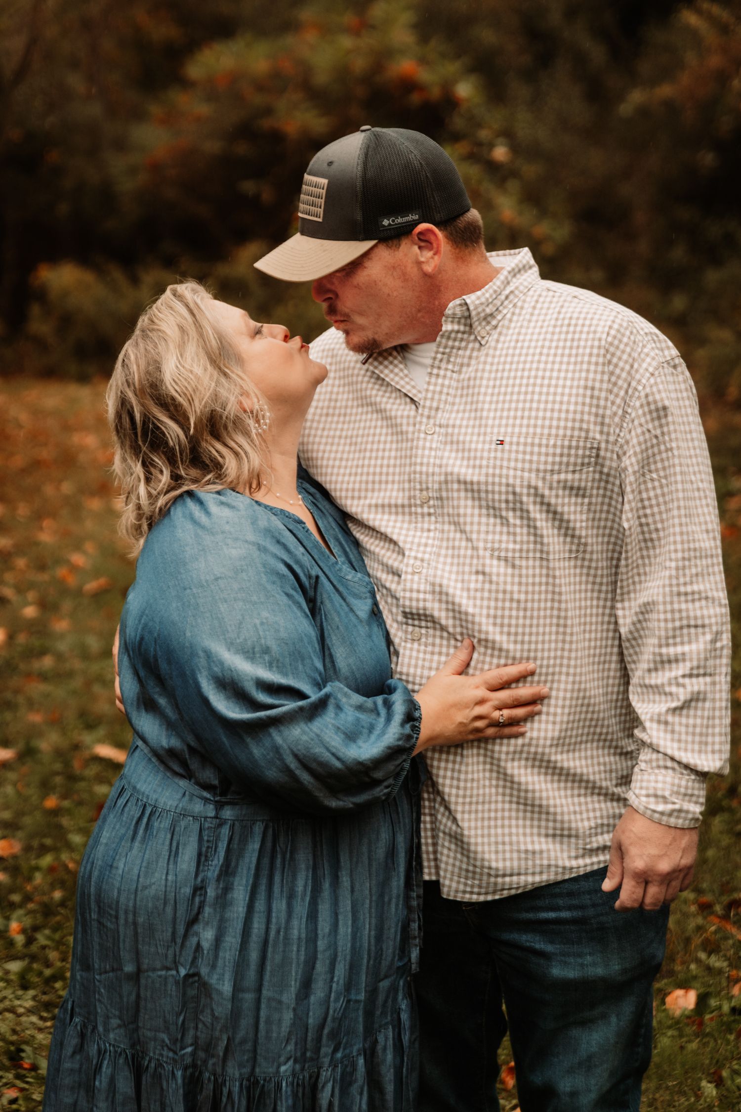 A romantic autumn scene of a couple sharing an intimate moment in a park with fallen leaves in the background.