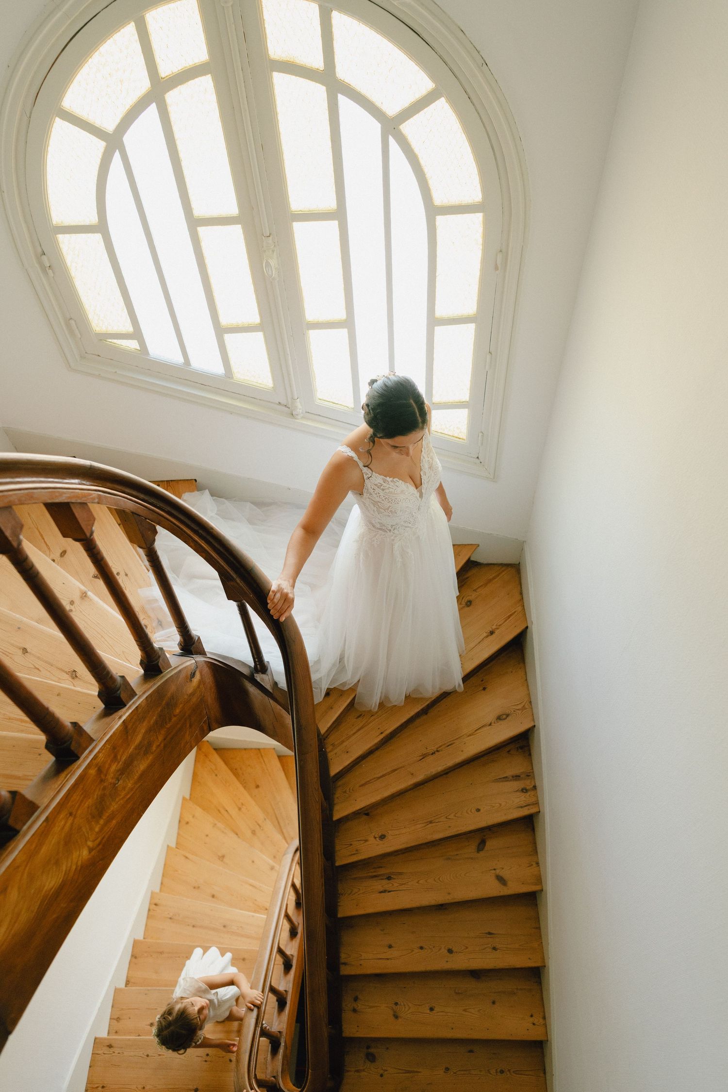 photo mariée descendant de l'escalier, une main sur la rembarde, sa fille la regarde d'en bas, tenant aussi à la rembarde.