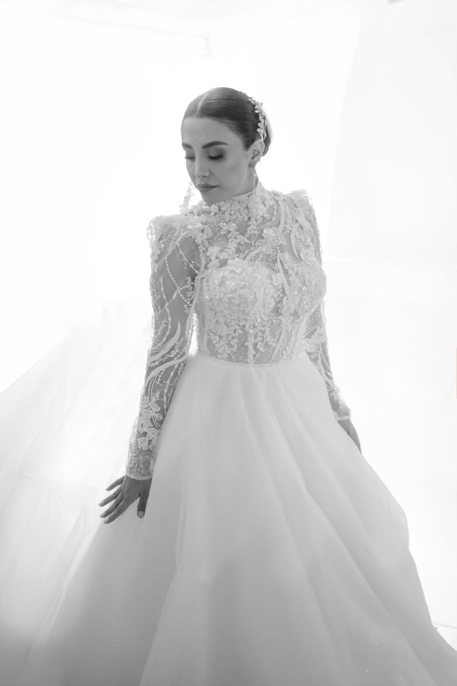 Ethereal black and white portrait of a flowing white wedding gown with lace details.