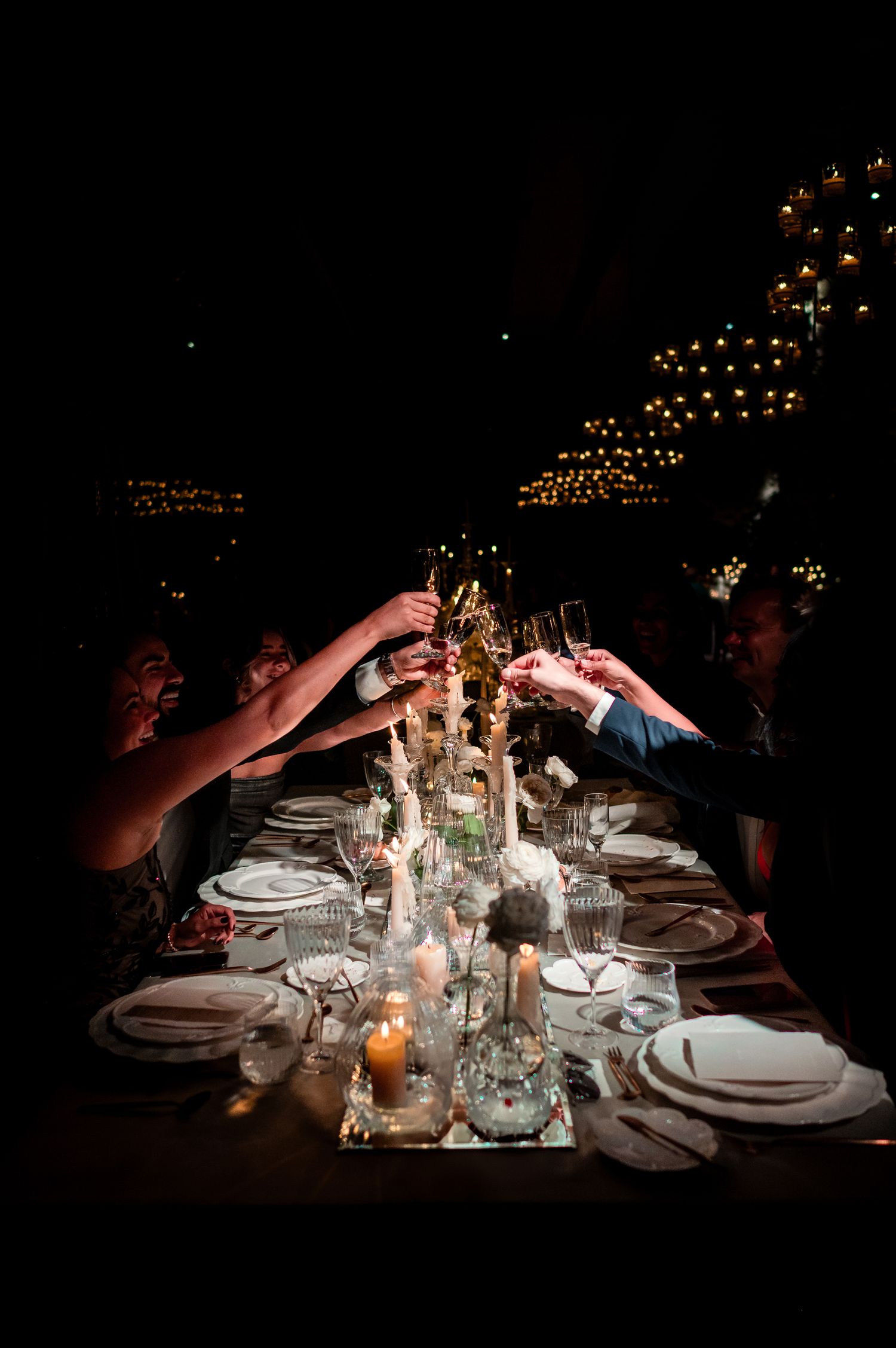 Candlelit wedding reception table with elegant place settings and glowing ambient lighting.