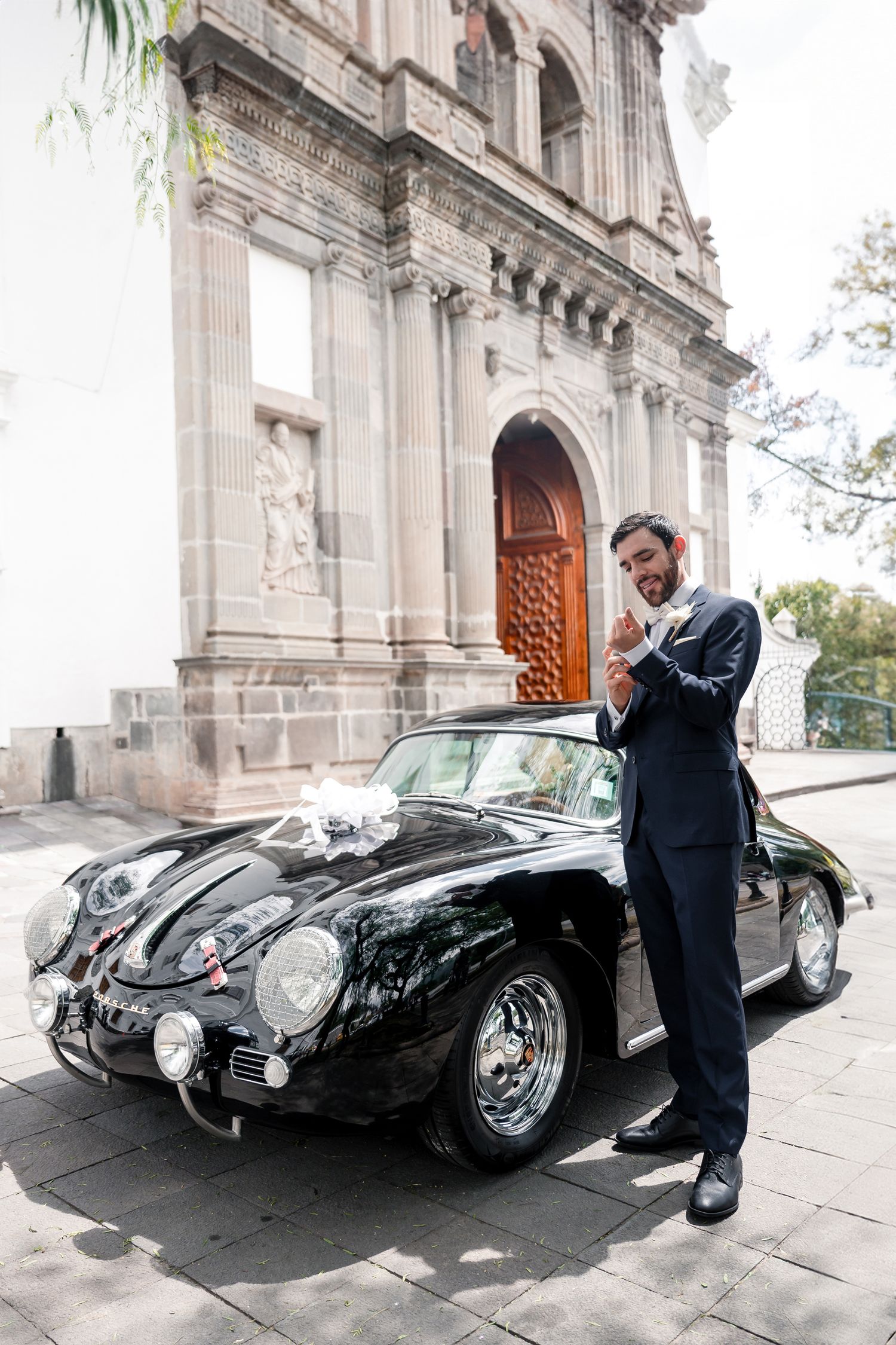 Classic black Porsche 356 parked in front of ornate church doors with elegant architectural details.