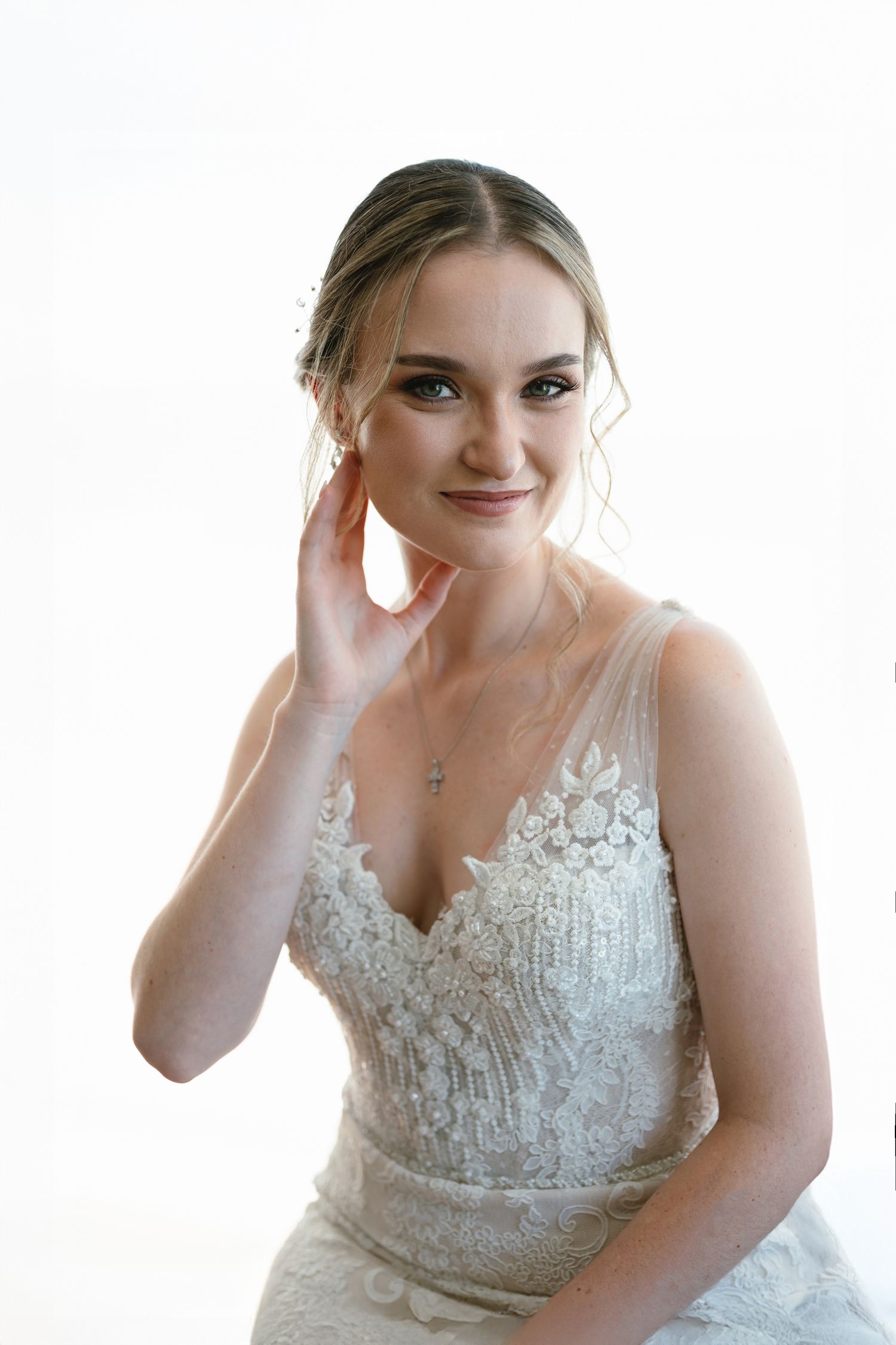Bride in white lace wedding dress poses expressively against bright background.
