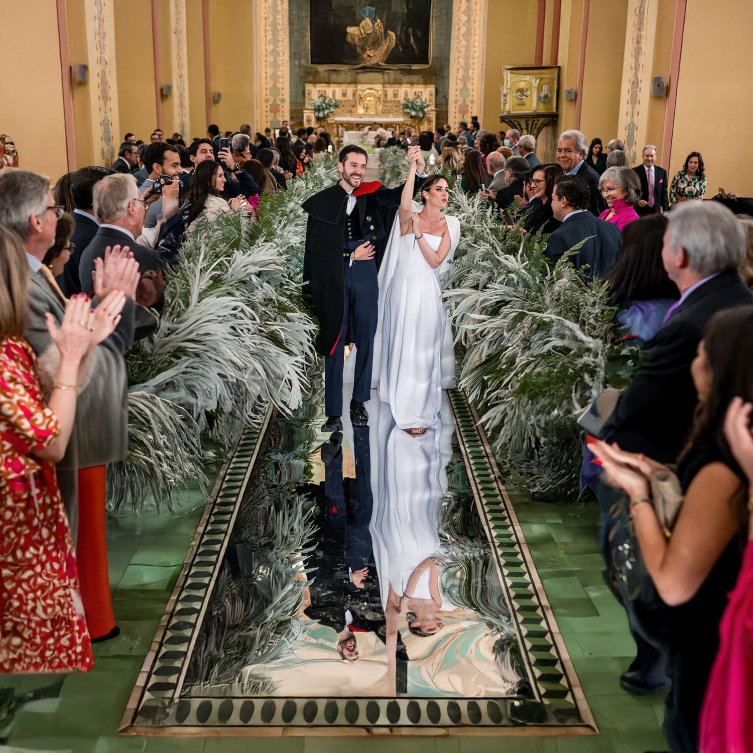 Wedding ceremony in elegant ballroom with palm fronds and gold accents.
