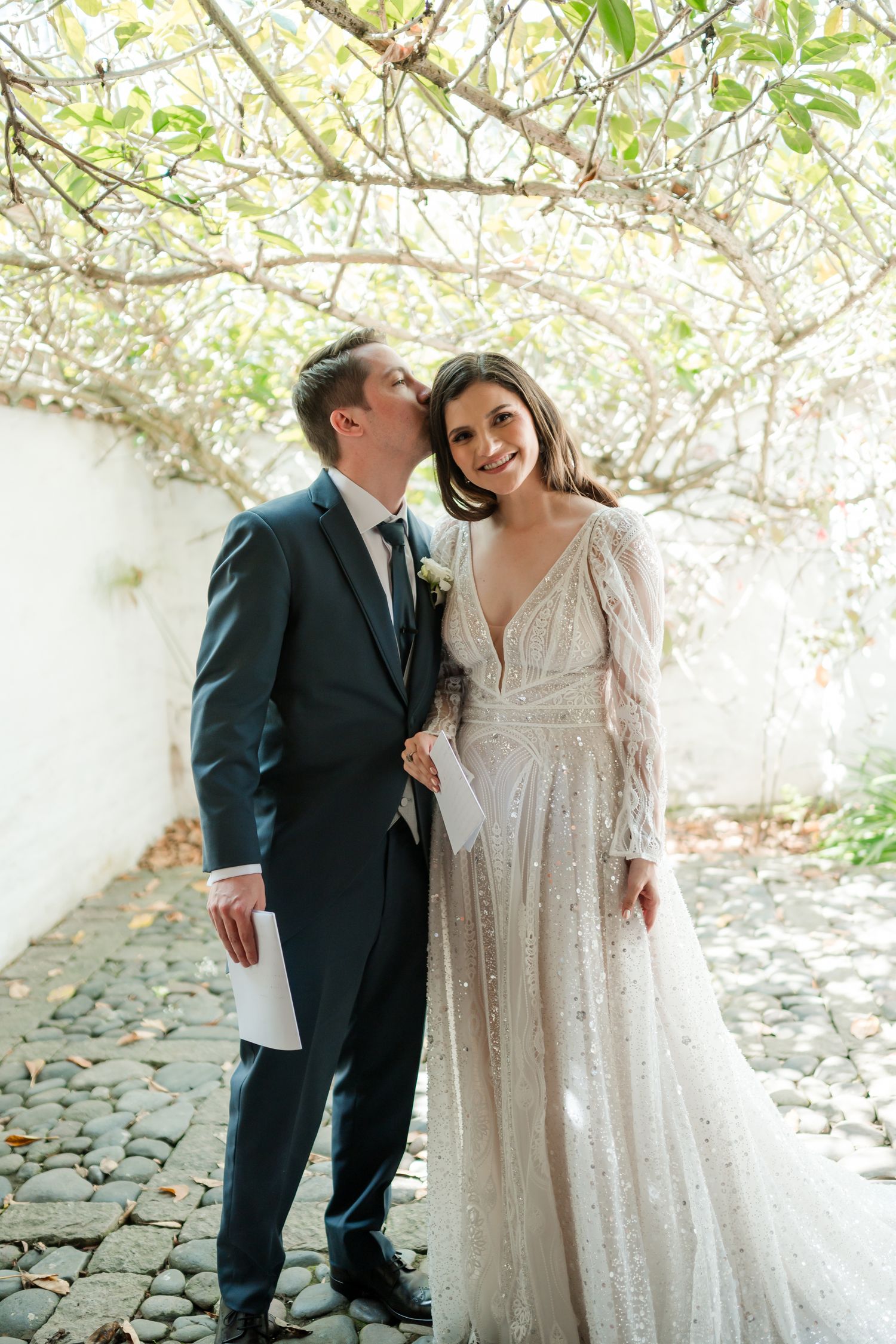 Wedding couple sharing intimate moments under blooming spring trees.