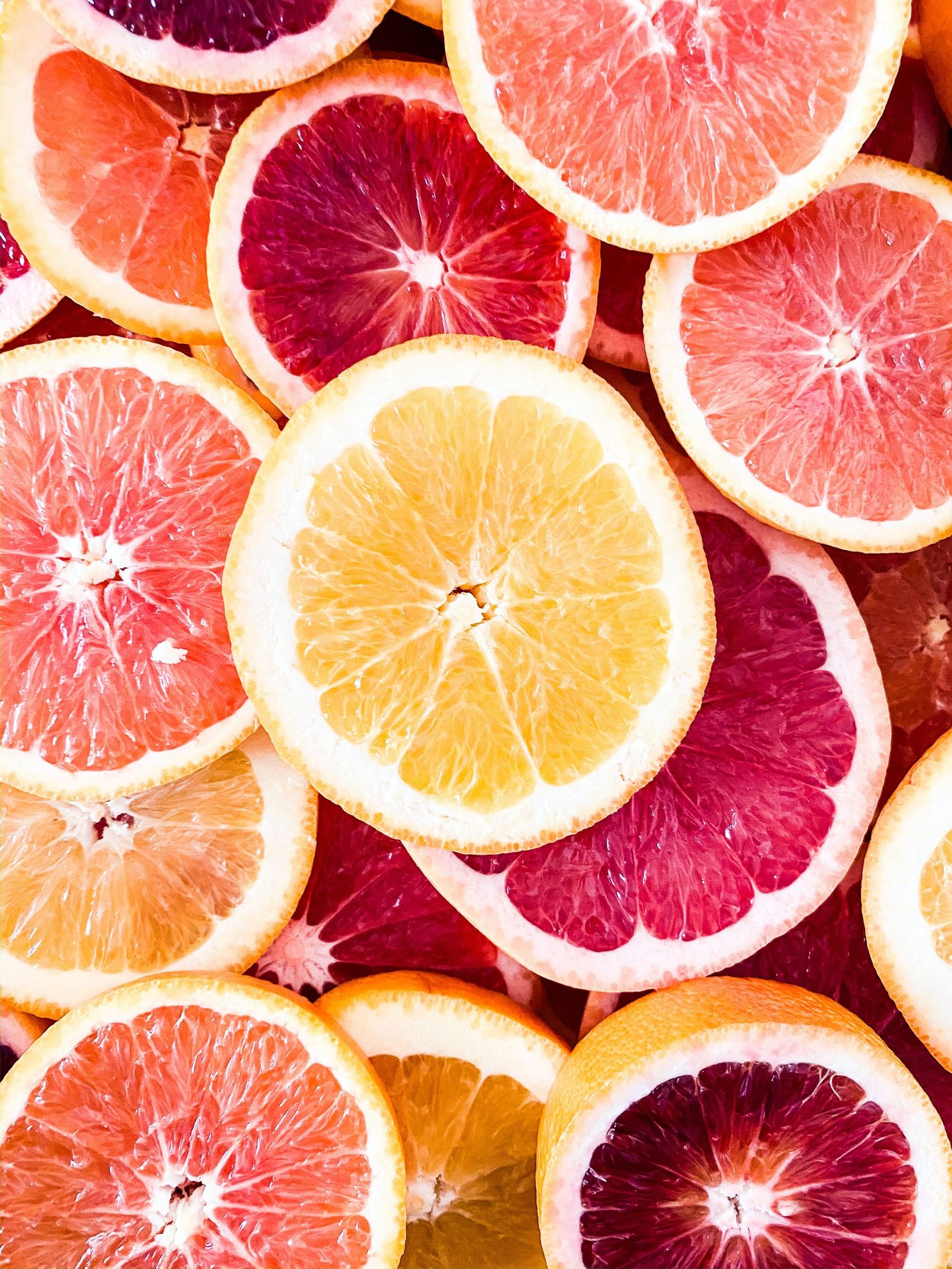 Colorful sliced citrus fruits including blood oranges, grapefruits, and lemons arranged in an overhead flat lay.