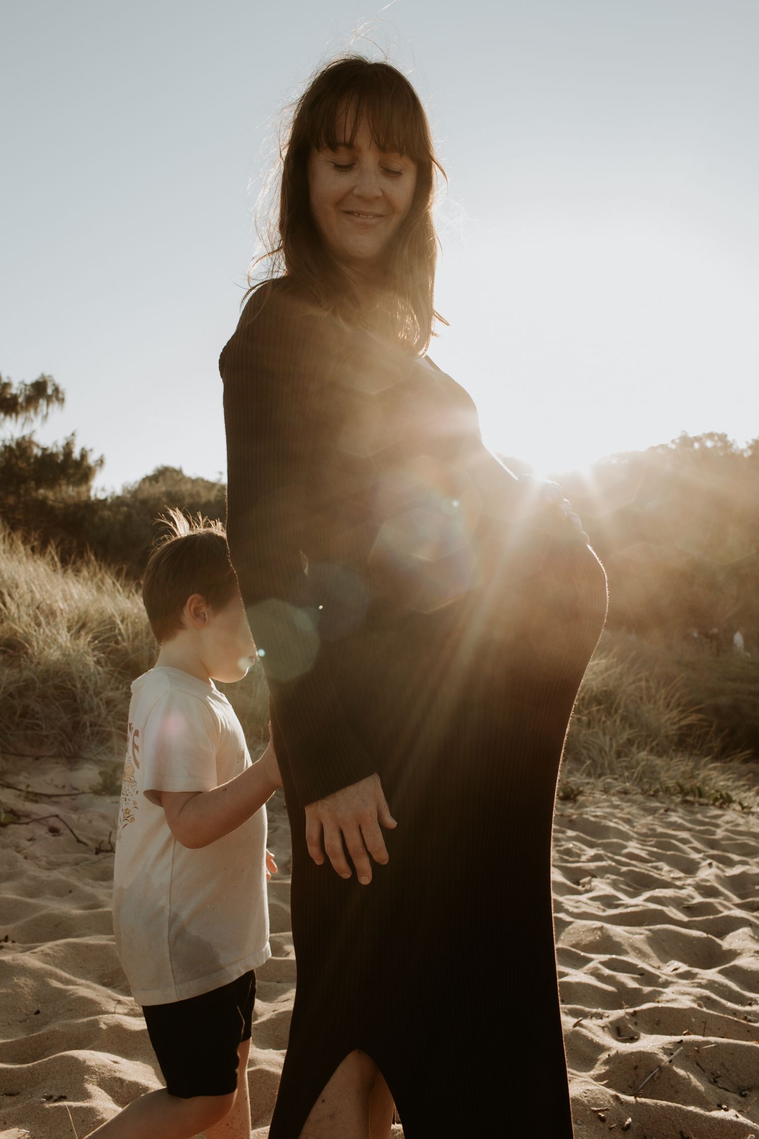pregnant mum and son with sun flare at sunshine coast beach