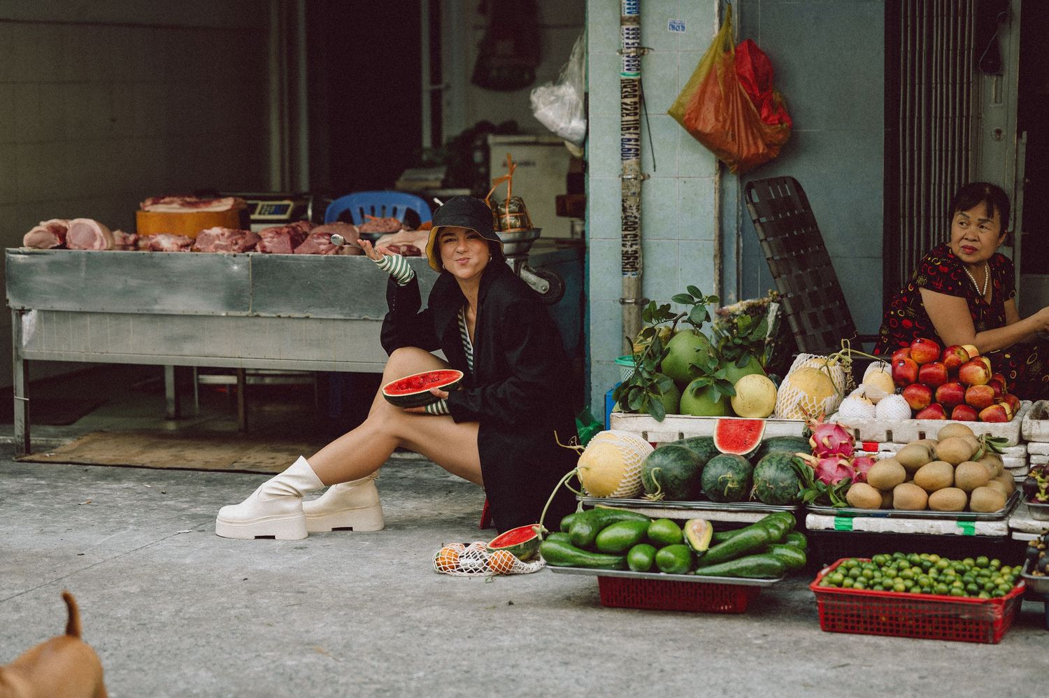 Model seated among fruit stalls at Banana Garden Market, Ho Chi Minh City — editorial lifestyle photography