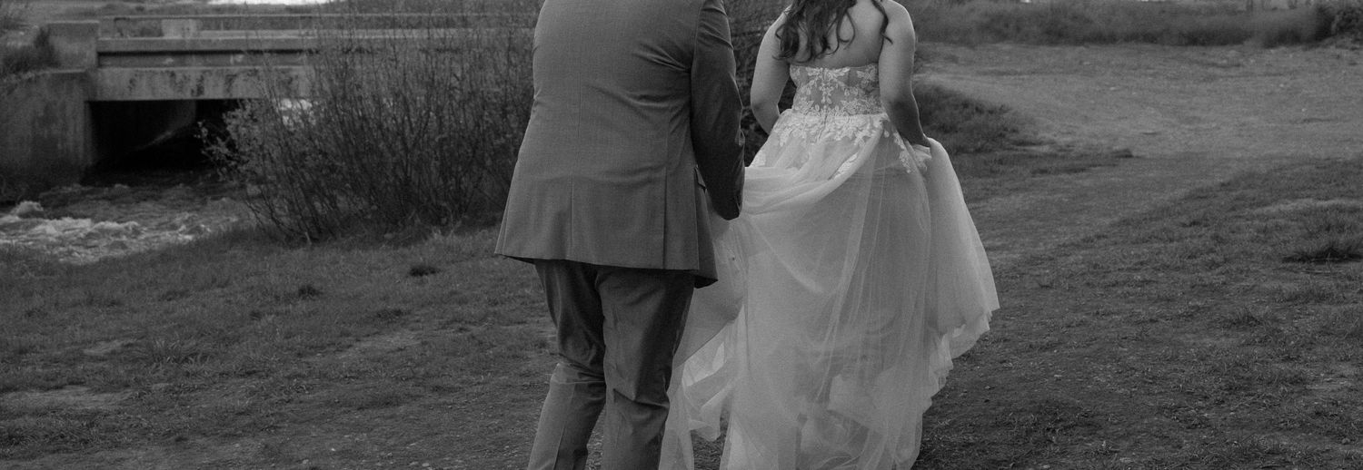A couple shares an intimate moment under tall trees in monochromatic black and white wedding photography.