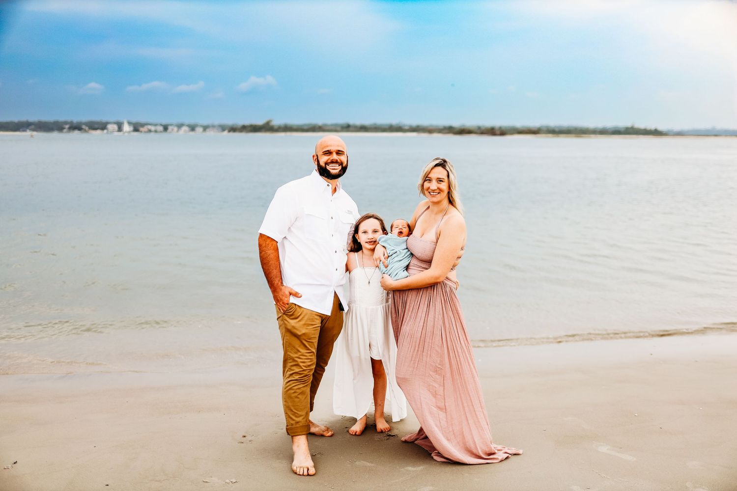 a new family of four smiles on the beach